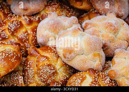 Traditionelles mexikanisches Pan de Muerto (Brot der Toten) mit Sesamsamen, gestapelt in einem rustikalen Korb. Köstliches, kultiges „Day of the Dead“-Essen. Stockfoto