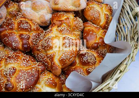 Traditionelles mexikanisches Pan de Muerto (Brot der Toten) mit Sesamsamen, gestapelt in einem rustikalen Korb. Köstliches, kultiges „Day of the Dead“-Essen. Stockfoto