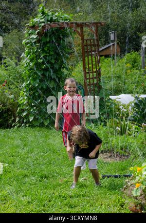 Zwei Kinder spielen an einem heißen Sommertag im Gemeinschaftsgarten in Maine, USA Stockfoto