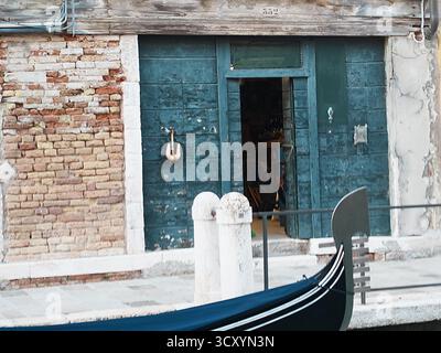 Der geschlossene Holzeingang zu einem Wohngebäude in Venedig, Italien. Eine Gondel davor Stockfoto