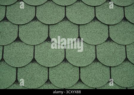 Nahaufnahme von grünen Asphaltdachschindeln, die ein Muster bilden. Ideal für Bau-, Architektur-, Hintergrund- oder Dachkonstruktionsprojekte. Stockfoto