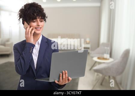 Hotelverwalter telefoniert und hält den Laptop im Zimmer Stockfoto