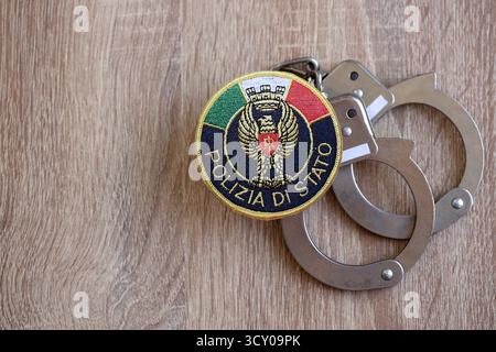 KIEW, UKRAINE - 6. SEPTEMBER 2025 Flicken der italienischen Staatspolizei und alte Handschellen aus Metall auf dem Tisch in Nahaufnahme Stockfoto