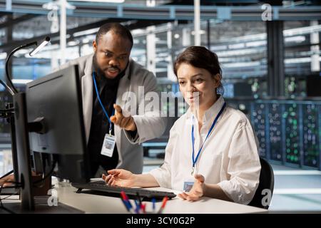 Rechenzentrumsmanager überwacht die Arbeit des Technikers, der die Servertechnik aktualisiert und Geräte mithilfe von Software konfiguriert. Server-Hub-Supervisor, der den Mitarbeiter überwacht, der Hardwareanalysen überprüft Stockfoto