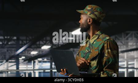 Militärtechniker im Serverraum der Kommandozentrale mit Laptop zur Installation und Wartung von IT-Systemen. Administrator des militärischen Rechenzentrums, der Computernetzwerke und Informationssysteme überwacht Stockfoto