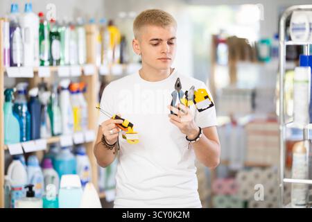 Porträt eines jungen männlichen Käufers, der Werkzeuge für die Reparatur in der Eisenwarenabteilung des Supermarktes wählt Stockfoto