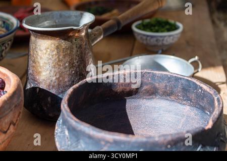 Alte Keramikschale und traditioneller Kupferkaffee für die Kaffeezubereitung auf rustikalem Holztisch Stockfoto