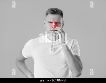 Junger Mann mit verletzter Nase auf grauem Hintergrund Stockfoto