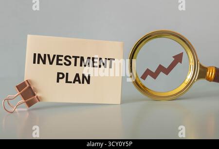 Ein farbiger Holzblock mit Text INVESTITIONSPLANUNG neben weißem Wecker. Geschäfts- und Finanzplanungskonzept Stockfoto