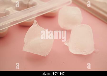 Eiswürfel auf rosa Oberfläche in einer Küche verstreut Stockfoto