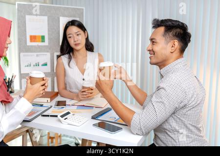 Eine Gruppe verschiedener Geschäftsleute, die in einem modernen Büro zusammenarbeiten und Diagramme und Datenanalysen während eines Meetings besprechen. Die Atmosphäre spiegelt sich wider Stockfoto
