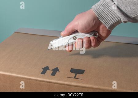 Schneiden großer Kartonverpackungen mit dem Universalmesser Stockfoto