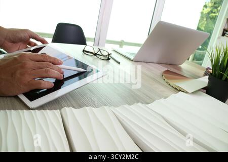 Architekt mit digitalem Tablet und Eingabestift neben Laptop und Materialproben auf Holztisch. Moderne Arbeitsumgebung, die Kreativität, Stockfoto