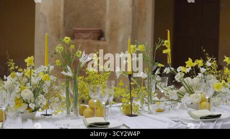 Elegantes Ambiente mit gelben Blumen und Zitronen im historischen Veranstaltungsort. Aktion Stockfoto