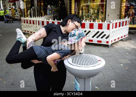 Deutschland Deutschland Berlin Eine Frau hält ein Mädchen über einem Wasserstrom, der aus einem öffentlichen Wasserspender am Kurfürstendamm strömt. Berlins Wasserwerk o Stockfoto
