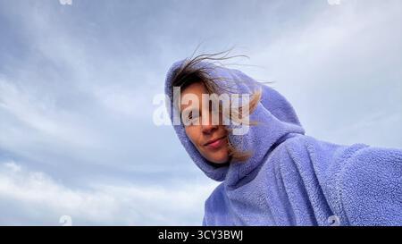 Selfie einer jungen Frau in einem violetten Hoodie am Himmel Stockfoto