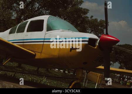 Ein auffälliger, flacher Schuss, der den vorderen Rumpfbereich eines klassischen einmotorigen Propellerflugzeugs zeigt. Der hellgelbe Körper, kontrastierend weiß Stockfoto