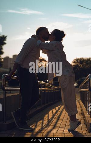 Ein Paar küsst sich bei Sonnenuntergang auf der City Street und genießt einen romantischen Moment Stockfoto
