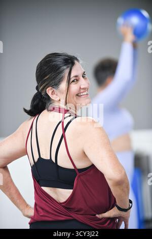 Lächelnde Frau in Workout-Kleidung im Fitnesskurs, Rückblick. Stockfoto