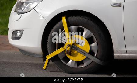 Krakau, Polen, Oktober 2025. Detaillierte Nahaufnahme einer gelben Radklemme, die an einem Autoreifen angebracht ist, um Bewegungen aufgrund von illegalem Parken zu verhindern. Conce Stockfoto