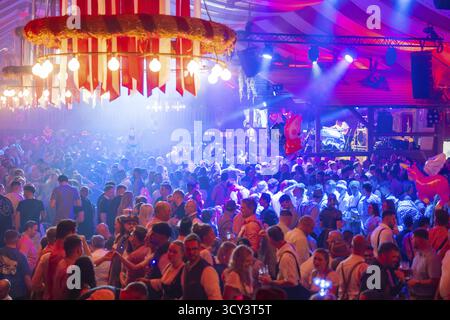Eine lebhafte Party in einem festlichen Bierzelt mit Bühne und beleuchteter Atmosphäre bei Nacht, Volksfest Cannstatter Wasen, Sonja Merz Festzelt, Stuttgart, Ger Stockfoto