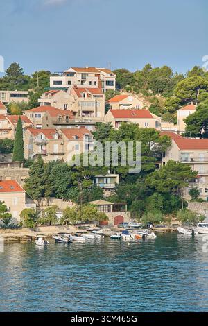 Steinhäuser mit Terrakottadächern auf einem grünen Hügel an der Adria. Kleine Freizeitboote liegen in der ruhigen Bucht vor Anker. Stockfoto