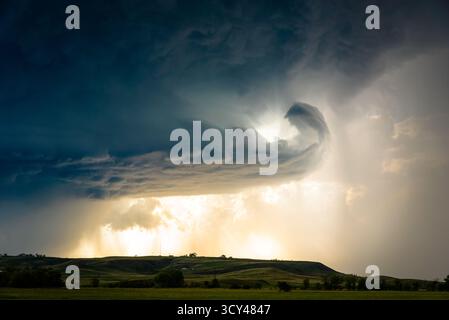 Unglaubliche Gewitterwolken und Kontrastturme über grünen Hügeln, die dramatischen Himmel, lebendige Landschaft, natürliche Spannung und sanftes Gelände verbinden Stockfoto