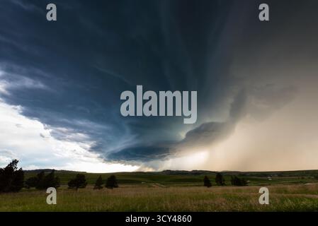 Erstaunliche Sturmwolken schweben über üppiges Ackerland und vermischen dramatischen Himmel, lebhafte grüne Felder, atmosphärische Spannung, ländliche Landschaft, und Leistung Stockfoto