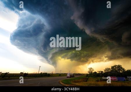 Eine atemberaubende Sturmwolke erhebt sich über einer Autobahn und entfesselt einen riesigen Hagel und einen Tornado, der extremes Wetter, mächtigen Himmel und intensive Action zeigt Stockfoto