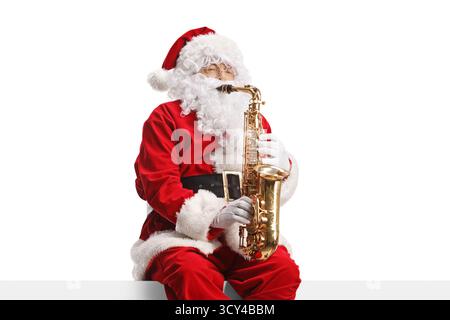 Weihnachtsmann spielt Saxophon und sitzt an einer Wand Stockfoto