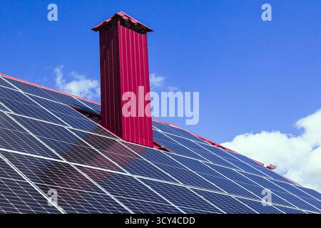 Sonnenkollektoren auf dem Dach eines Privathauses mit Kamin. Alternative Energie eines Privathauses. Grüne Energie Stockfoto