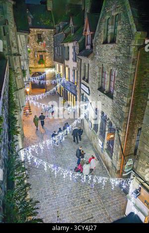 MONT SAINT-MICHEL, FRANKREICH – 15. DEZEMBER 2024: Touristen schlendern entlang einer charmanten, beleuchteten Kopfsteinpflasterstraße im historischen Mont Saint-Michel in n Stockfoto