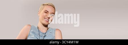 Selbstbewusste junge Frau mit kurzen Haaren zeigt ihr Gespür für Mode, während sie eine verspielte Pose zeigt. Stockfoto