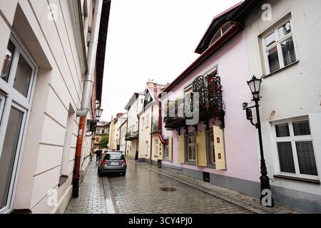 Tarnow, Polen - 10. Oktober 2025: Malerische Straße in Tarnow mit pastellfarbenen Fassaden, blühendem Balkon und Kopfsteinpflaster. Stockfoto