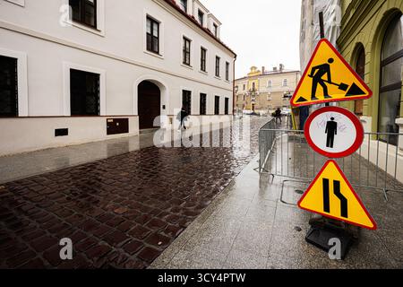 Tarnow, Polen - 10. Oktober 2025: Nasse Kopfsteinpflasterstraße in Tarnow mit Schildern, Barrieren und Fußgängerzone. Stockfoto