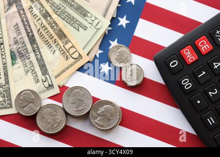 US-Dollar-Geldscheine und Taschenrechner auf amerikanischer Flagge Nahaufnahme. Geldinvestitionskonzept und Steuerzahlung Stockfoto