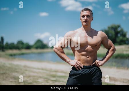 Muskulöser junger Mann, der die sonnige Umgebung am See genießt Stockfoto