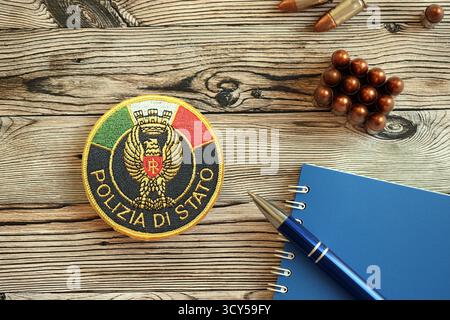 KIEW, UKRAINE - 6. SEPTEMBER 2025 Flicken der italienischen Staatspolizei mit Kugeln und Notizblock auf Holztisch Nahaufnahme Stockfoto