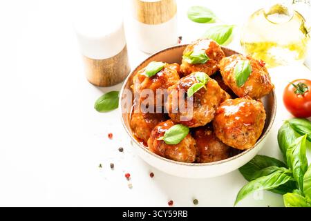 Fleischbällchen in Tomatensauce, glasierte Fleischbällchen in Bastelplatte auf weißem Tisch. Stockfoto