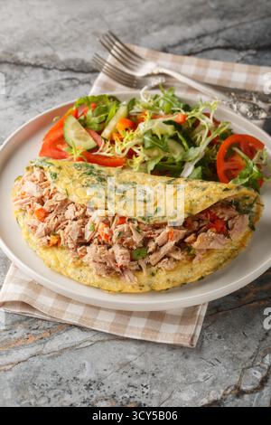 Omelette mit Thunfisch aus der Dose serviert mit frischem Gemüse Salat in der Nähe auf dem Teller auf dem Tisch. Vertikal Stockfoto