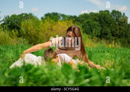 Mutter mit Kind, die Spaß im öffentlichen grünen Park hat. Glückliche Mutter lacht zusammen mit dem Sohn. Hochwertige Freizeit im Freien. Stockfoto