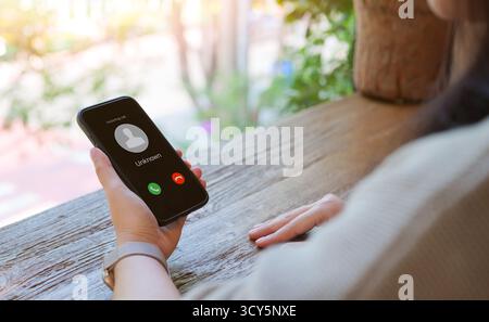 Frau, die ein Mobiltelefon hält und einen Anruf von einem unbekannten Anrufer eingeht. Betrüger oder Fremder, Betrüger mit gefälschter Identität, Streich-Anrufer, anonym, Fr. Stockfoto
