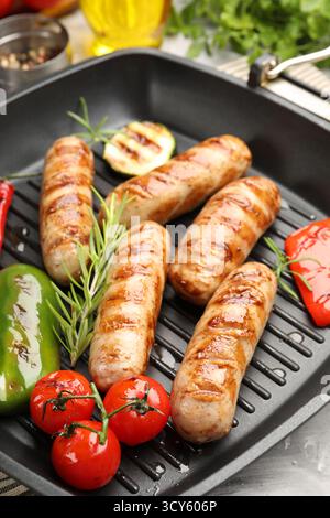 Pfanne mit gegrillten Würstchen, Gemüse und Gewürzen auf dem Tisch, Nahaufnahme Stockfoto