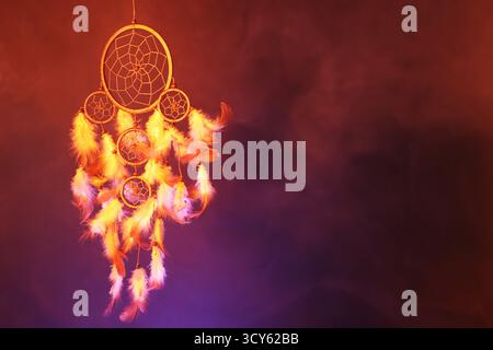 Schöner Traumfänger und Rauch in Farbe hell auf dunklem Hintergrund. Leerzeichen für Text Stockfoto