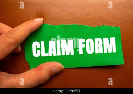 Antragsformular auf gerissenem, gerissenem, grünem Papierstück auf braunem Hintergrund. Symbol für das konzeptionelle Anspruchsformular. Kopierbereich. Stockfoto