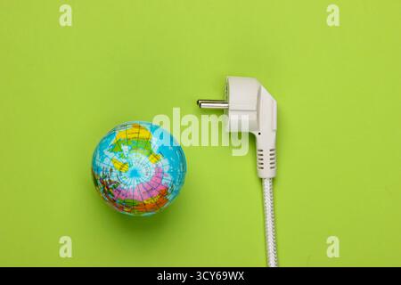 ECO-Konzept. Energiesparen Rettet den Planeten. Globus mit einem elektrischen Stecker auf grünem Hintergrund. Draufsicht Stockfoto