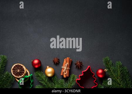 Weihnachten flach gelegt Hintergrund. Lebkuchenkekse, Gewürze, Tanne und Weihnachtsdekoration auf Schwarz. Stockfoto