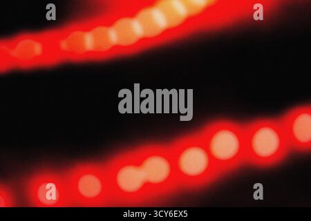 Sanfte rote Beleuchtung mit filmischer Unschärfe und körniger Staubüberlagerung für eine elegante, moderne Hintergrundstruktur für Design-, Film- und Digital Art-Profi Stockfoto