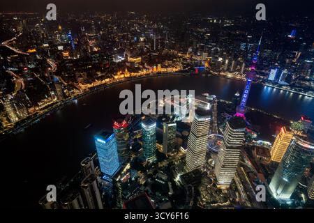 Blick aus der Vogelperspektive über den Bund, den Huangpu Fluss und das Finanzviertel Lujiazui mit beleuchteten Wolkenkratzern in Pudong in der Stadt Shanghai bei Nacht, China Stockfoto