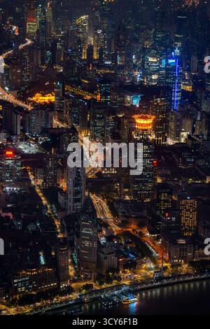 Blick aus der Vogelperspektive über den Bund, den Huangpu River und die beleuchteten Wolkenkratzer vom Shanghai Tower in Pudong in der Stadt Shanghai bei Nacht, China Stockfoto